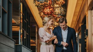 A couple walking in a hallway with wooden paneling and a decorative ceiling. - Ortners Resort (Bad Fuessing)