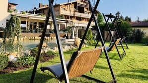 A garden with a swing set, a pool, and a building with balconies. - Ortners Resort (Bad Fuessing)