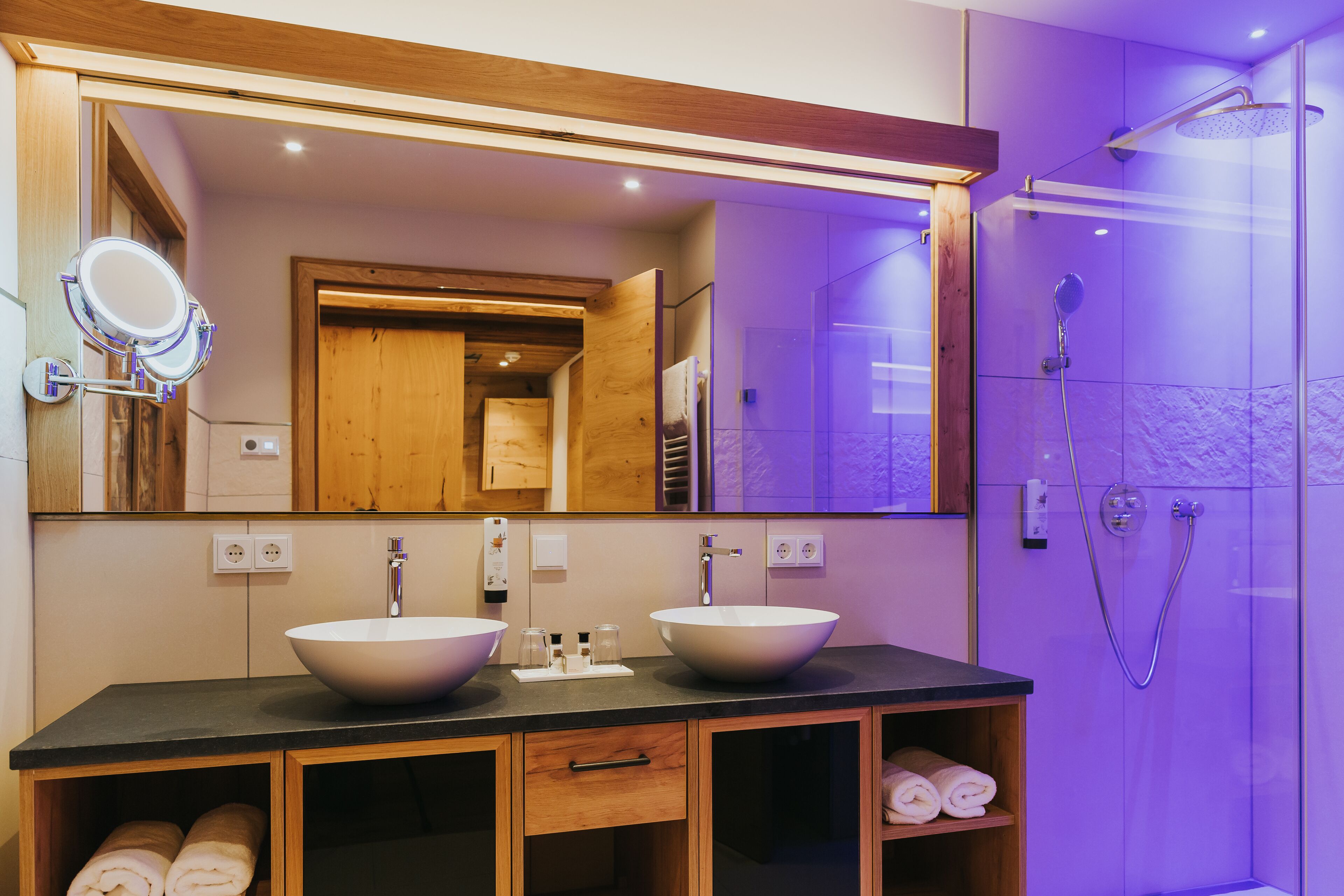 A modern bathroom with two large sinks, a mirror, and a shower.