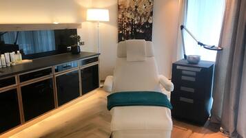 Et moderne værelse med en massagestol, et skrivebord med toiletartikler og et stort abstrakt maleri.