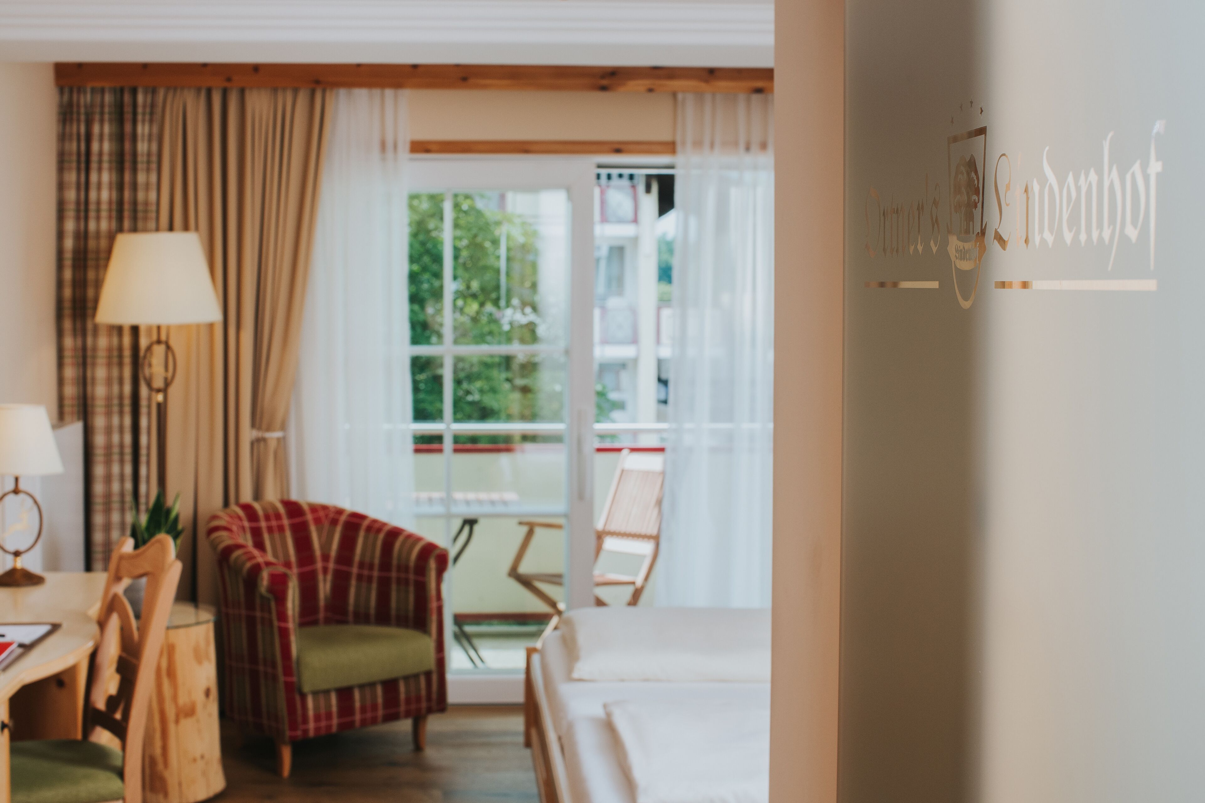 Habitación de hotel con cama, una silla, una mesa y un ventanal con cortinas.