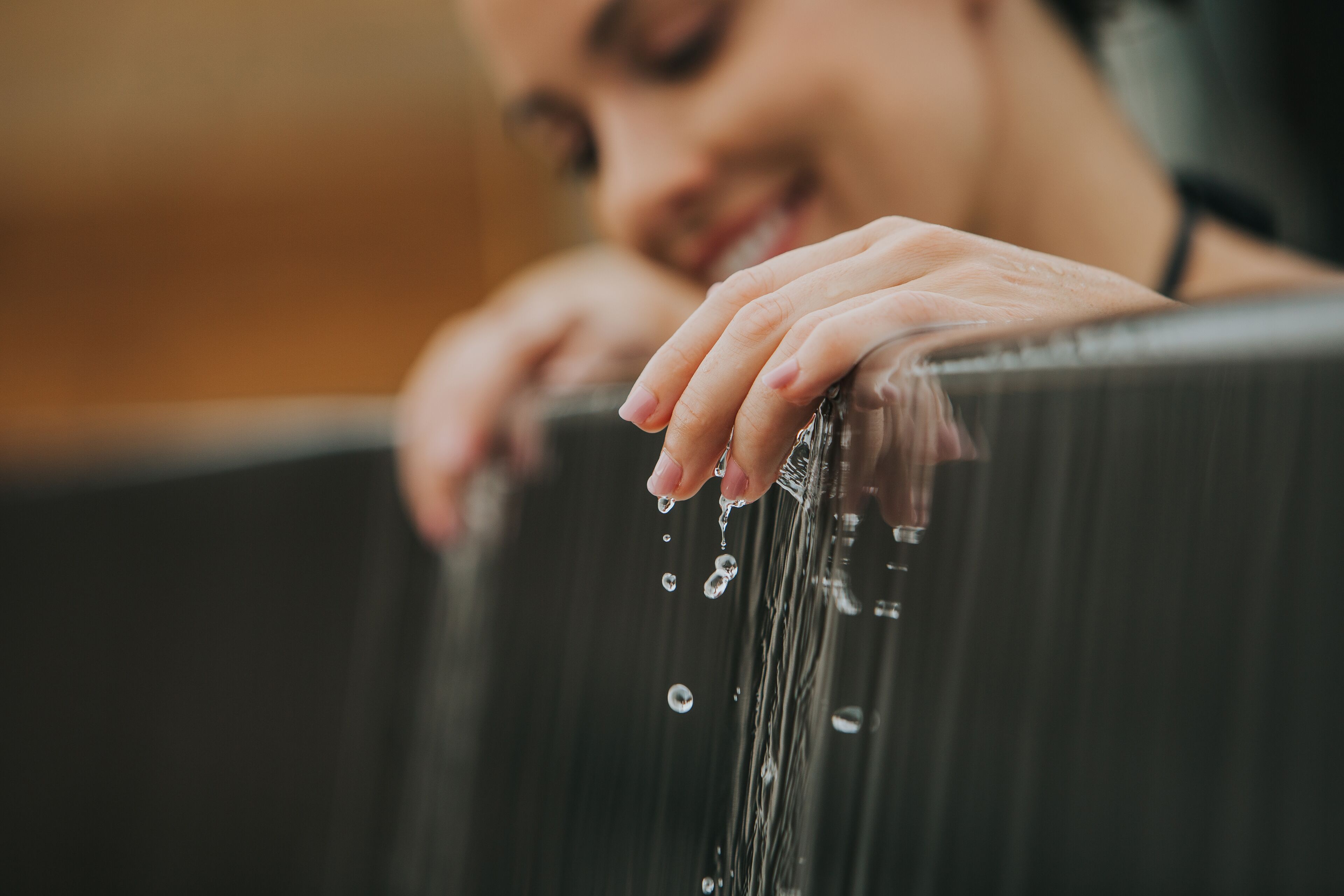 Un gros plan d’une main posée sur une surface en bois, avec des gouttelettes d’eau.