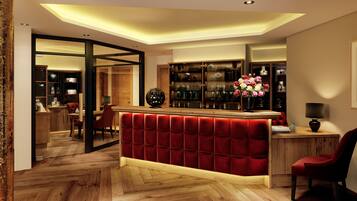 A modern hotel lobby with a red velvet reception desk, wooden flooring, and a glass partition separating the reception area from the dining space.