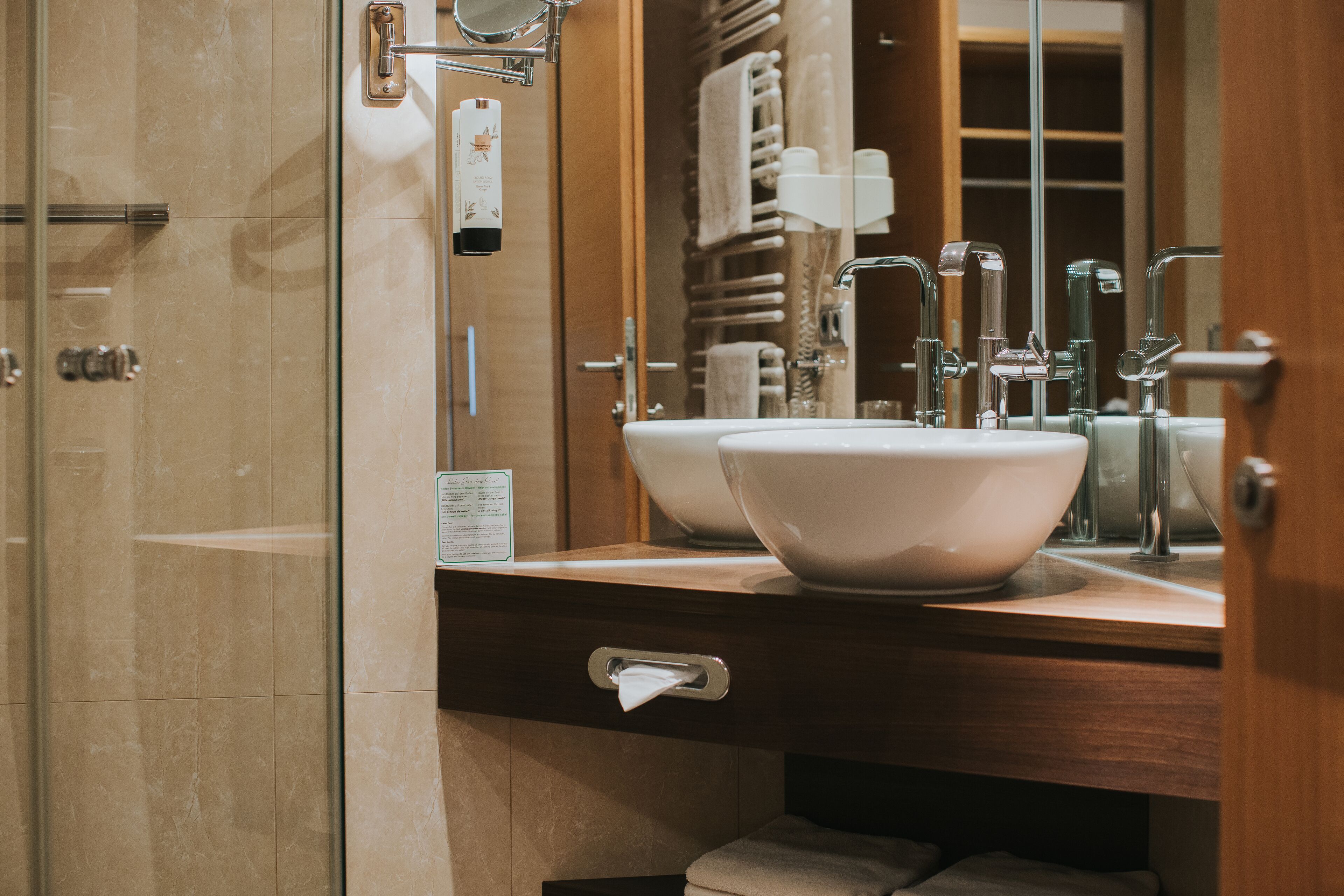A modern bathroom with two sinks, a mirror, and a towel rack.
