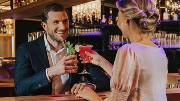 A bar setting with a man and a woman holding drinks.