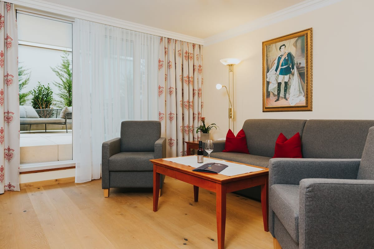 A living room with a grey sofa, a grey armchair, a wooden coffee table, and a painting on the wall.