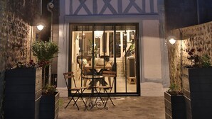 Een modern huis met een donkere gevel, een zichtbaar raam en een goed verlichte entree met een glazen deur.