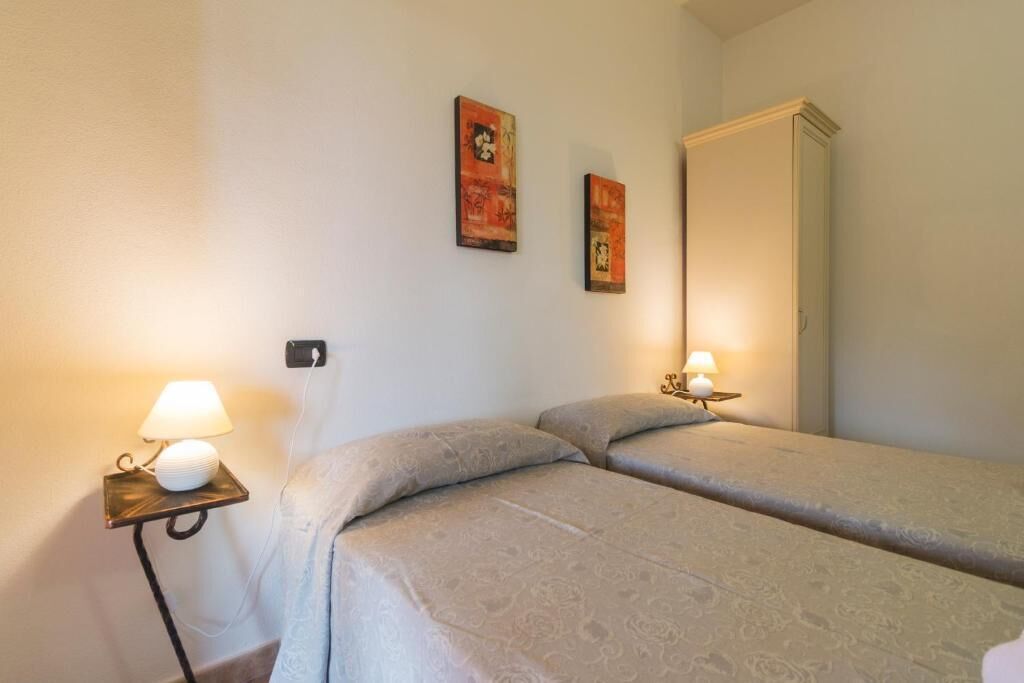 Een hotelkamer met twee bedden, nachtlampjes, een kledingkast en twee kunstwerken aan de muur.