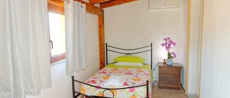 A bedroom with a bed, curtains, a nightstand, and a window.