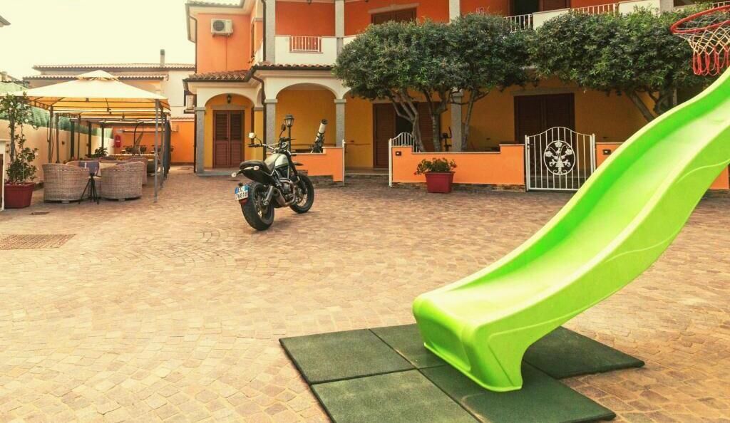A courtyard with a green slide, a motorcycle, and a covered seating area.