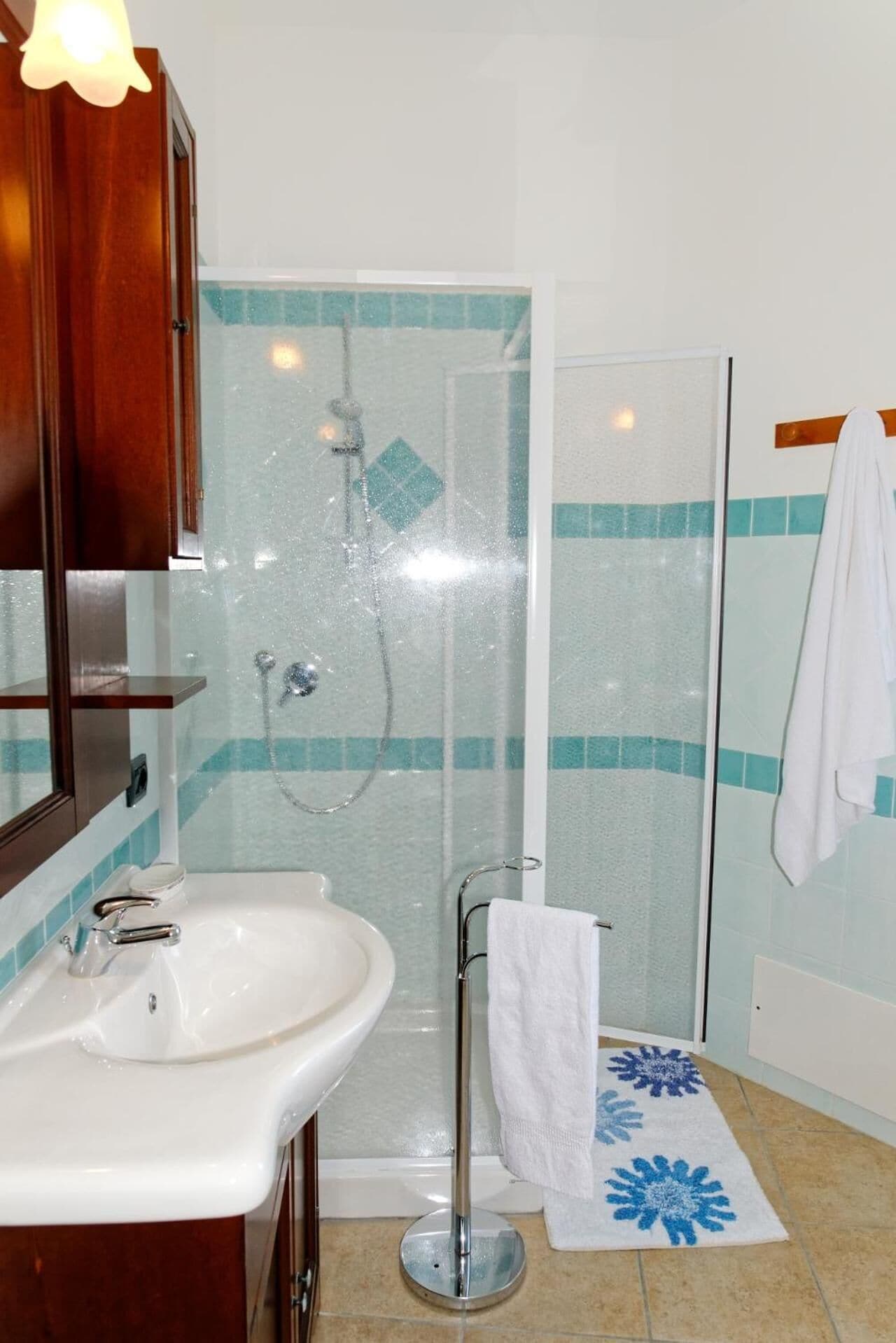 A bathroom with a glass-enclosed shower, a sink, and a towel rack.