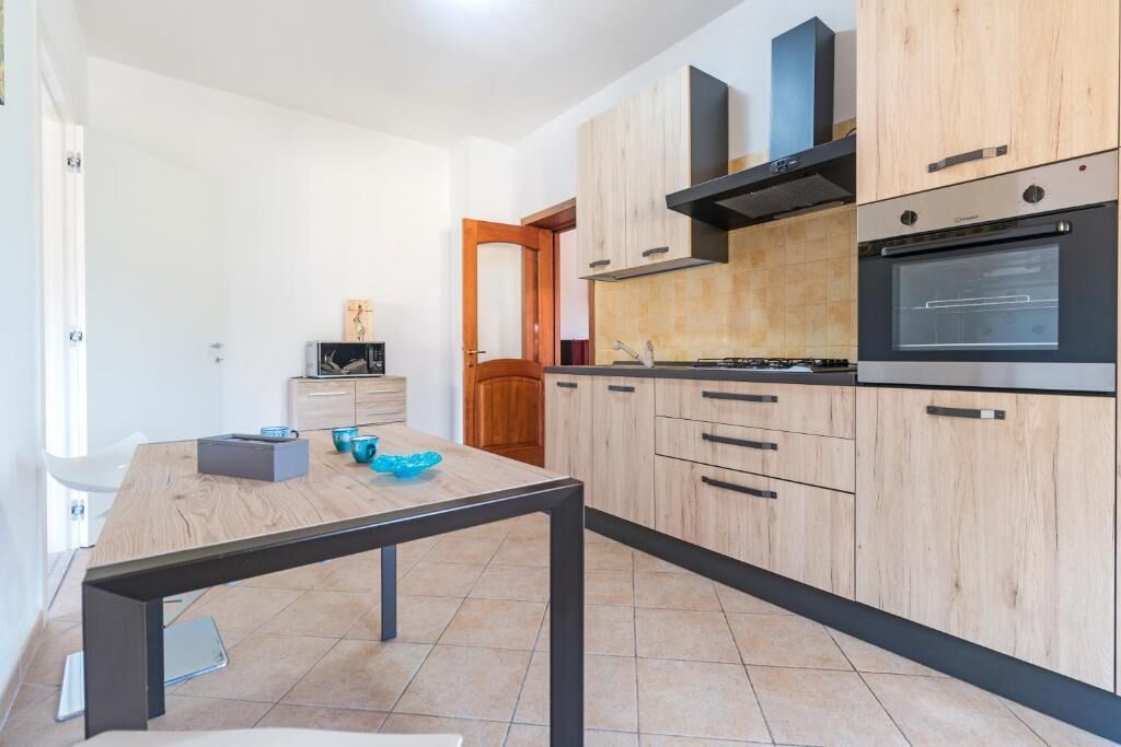 A modern kitchen with wooden cabinets, a built-in oven, and a dining table with chairs.