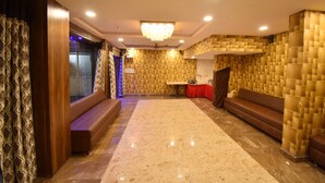 A lobby with a marble floor, a chandelier, a reception desk, and a seating area.