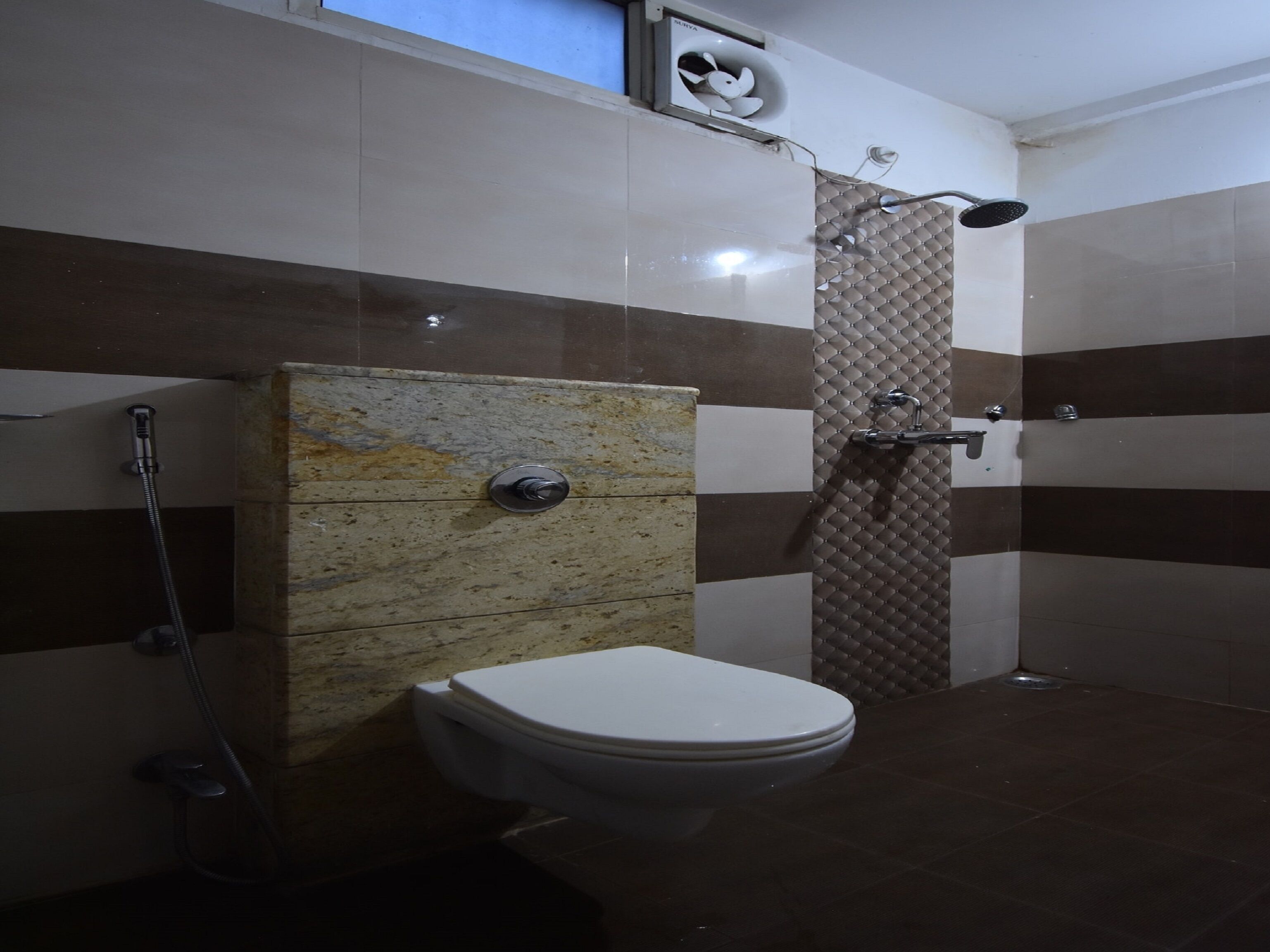 A bathroom with a toilet, a shower, and a wall-mounted air conditioning unit.
