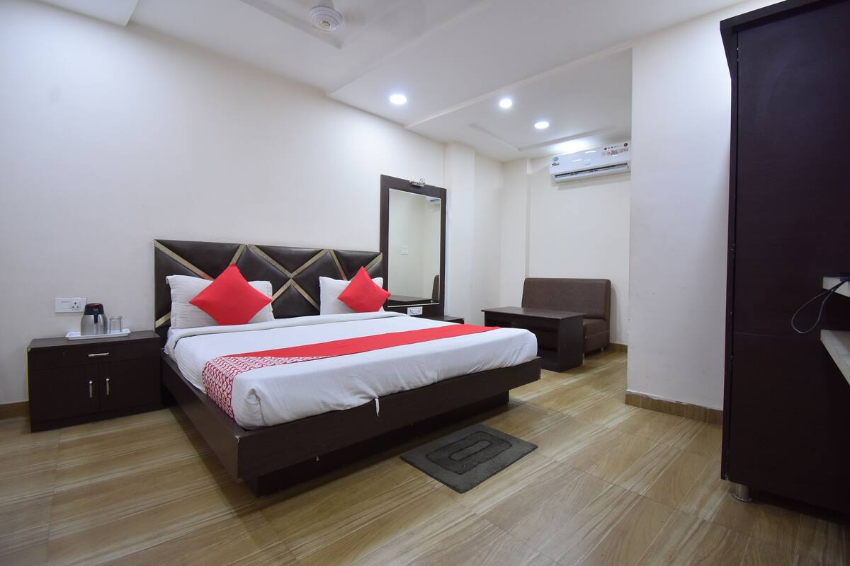 Habitación de hotel ordenada con una cama grande, mesitas de noche, una silla y un armario.