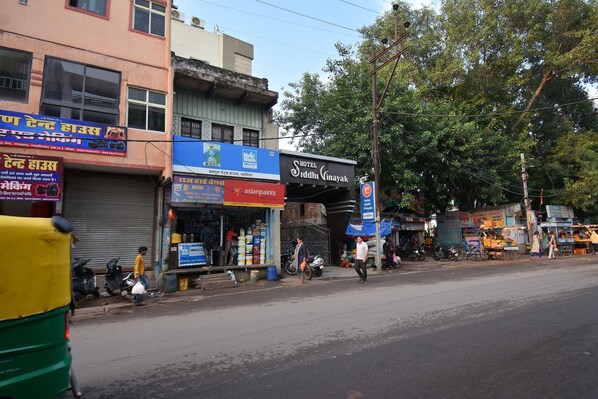 Vista de la calle con un hotel llamado 'Hotel Siddh Vinayak' y varias tiendas, incluyendo 'Asian Paints'.
