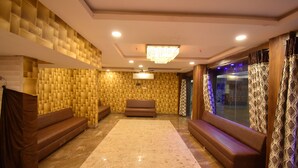 A spacious lobby with a patterned wall, a chandelier, and a seating area.