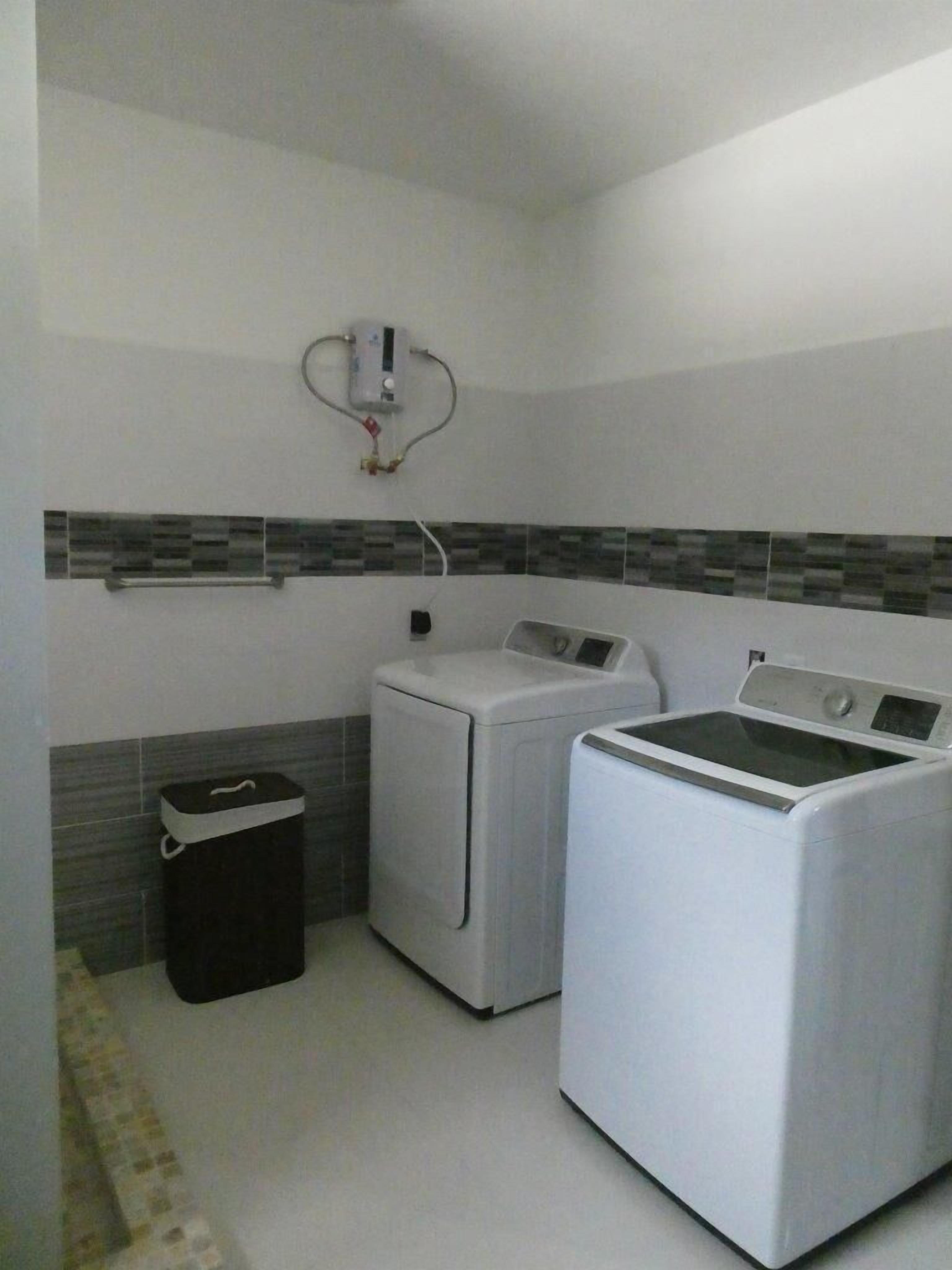 Une buanderie équipée de deux machines à laver, d’un sèche-linge et d’un chauffe-eau.