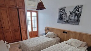 Una habitación con dos camas, un armario de madera, un escritorio y un cuadro de cebra colgado en la pared.