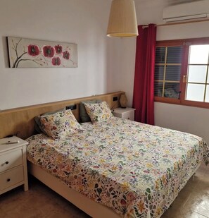 Ein Schlafzimmer mit Bett, Nachttisch, Lampe und einem Bild an der Wand.