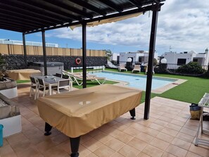 Ein Außenpoolbereich mit überdachter Lounge, Liegestühlen und einem Whirlpool.