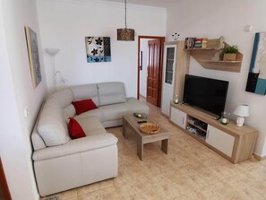 Ein Wohnzimmer mit einer Couch, einem Couchtisch, einem Fernseher und einem Bücherregal.
