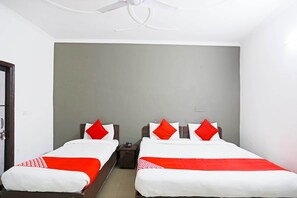 Une chambre d’hôtel avec deux lits, chacun agrémenté de draps rouges et blancs, un ventilateur de plafond et un mur d’accent de couleur grise.