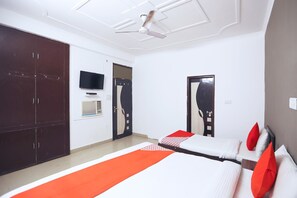 Une chambre d’hôtel équipée d’un lit, d’une armoire, d’une télévision et d’un ventilateur de plafond.