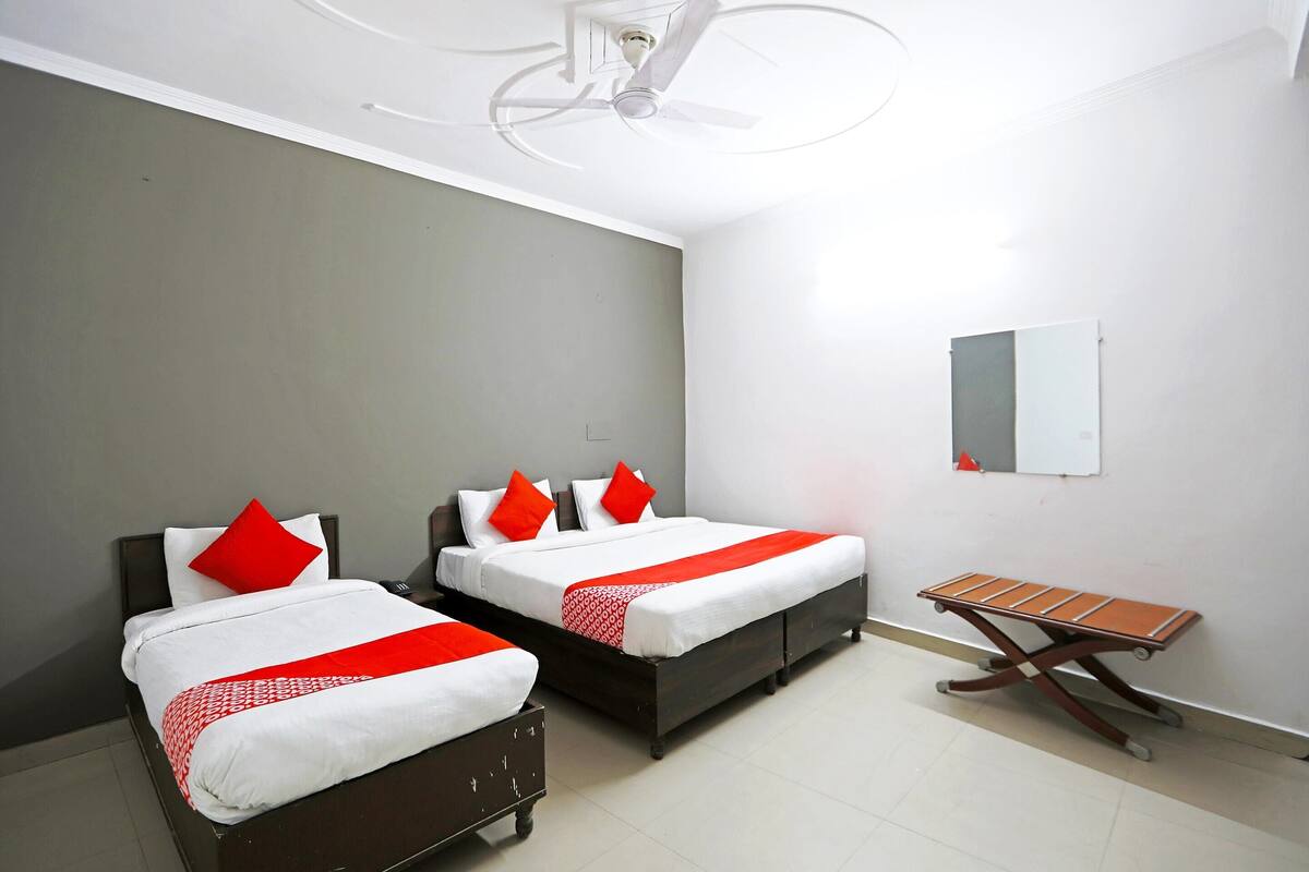 Une chambre d’hôtel avec deux lits, un ventilateur de plafond, une petite table et un miroir au mur.