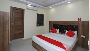 A hotel room with a bed, a ceiling fan, an air conditioning unit, and a wooden door. - OYO 30462 Hotel Ivy (New Delhi)