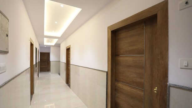 A hallway with wooden doors and a tiled floor, leading to a room with a wooden door. - OYO 30462 Hotel Ivy (New Delhi)