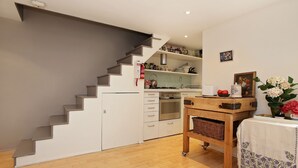 Una cocina moderna con armarios blancos, horno integrado y una mesa de madera con una cesta.