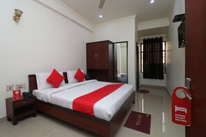 A hotel room with a bed, a wardrobe, a nightstand, a red sign, and a welcome mat.