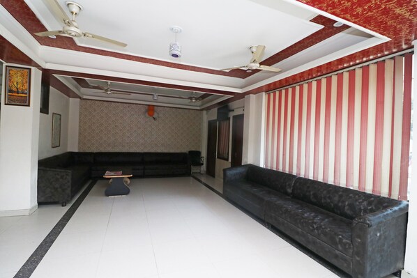 A spacious living room with a black sofa, a coffee table, and a ceiling fan.