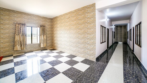 A hallway with a checkered floor, stone wall, and a view down a corridor.