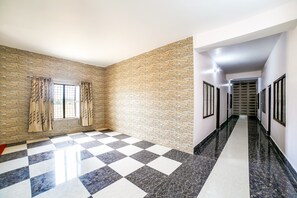 A hallway with a checkered floor, stone wall, and a view down a corridor. - OYO 37914 Hotel Kalindi (Vikasnagar)