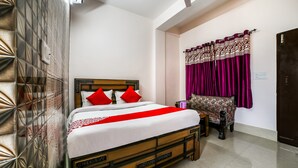 A neatly arranged bedroom with a wooden bed, a patterned sofa, and a decorative curtain.