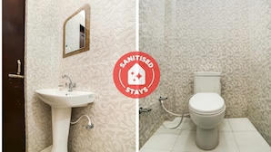 A bathroom with a sink, mirror, toilet, and patterned walls.