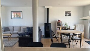 Ein modernes Wohnzimmer mit einer Couch, einem Esstisch und einem schwarzen Kaminofen.