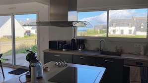 Eine moderne Küche mit einem großen Fenster, einem Einbauherd und einer Kaffeemaschine.