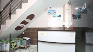 A room with a large window, a white refrigerator, and a metal ladder.