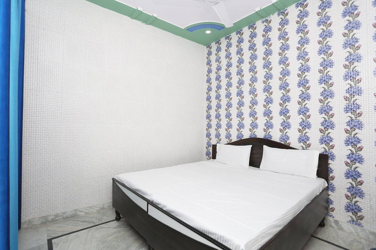 Een slaapkamer met een bed, hoofdeinde en behang met een patroon.