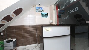 A hotel lobby with a reception desk, a security camera, and a wall with pictures.