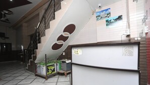 A hotel lobby with a staircase, a reception desk, and a wall with photos.