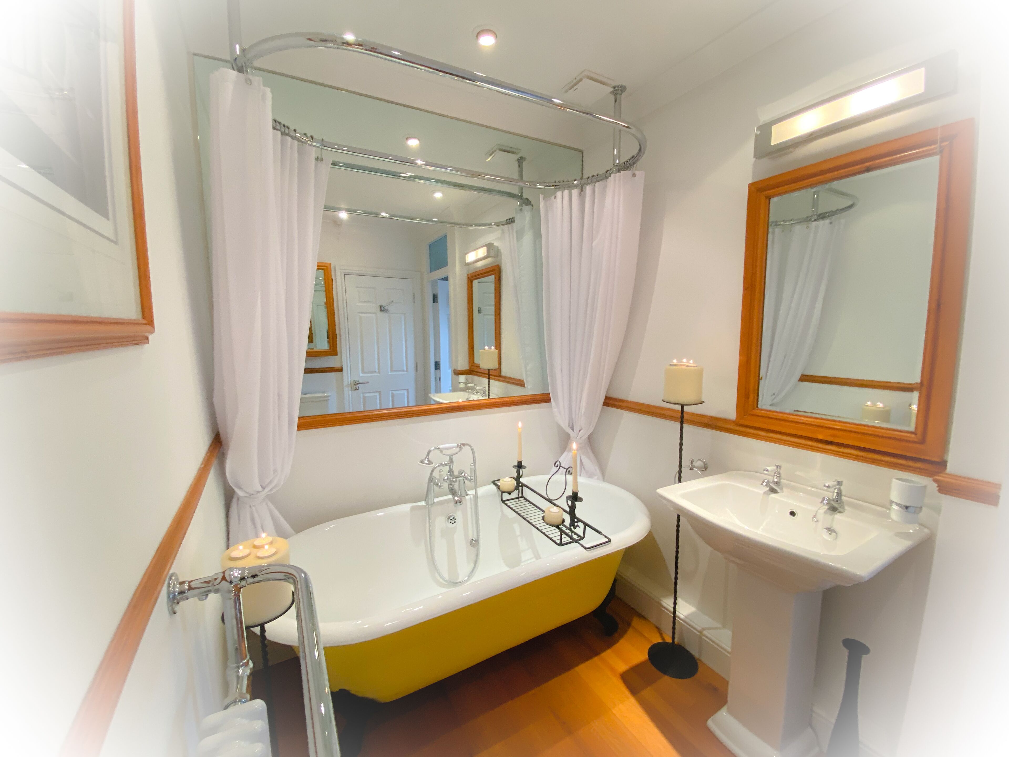 Een badkamer met een geel bad, een wit wastafelmeubel en een spiegel erboven.