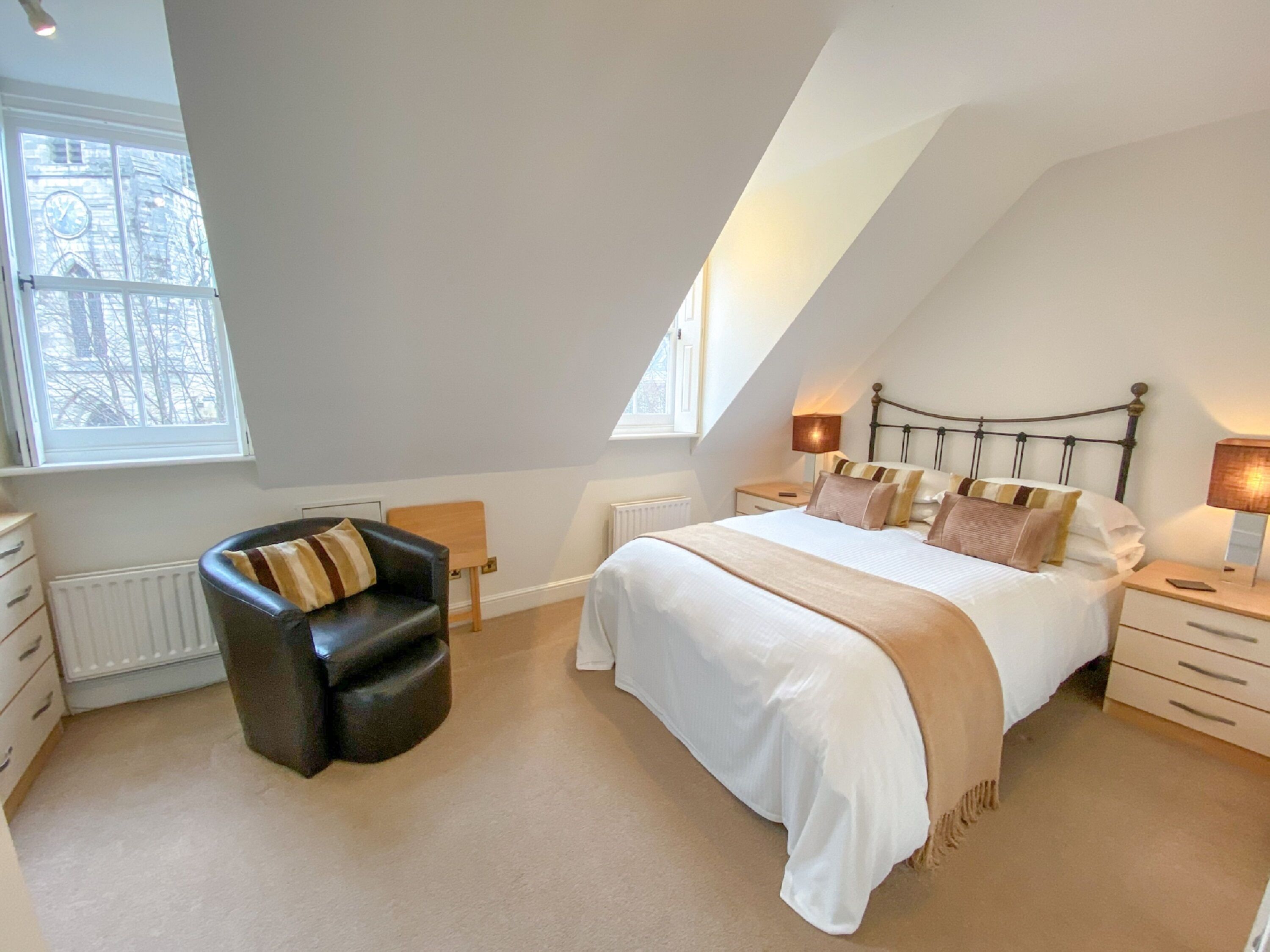 Une chambre à coucher avec un lit, une chaise, une commode et une fenêtre.