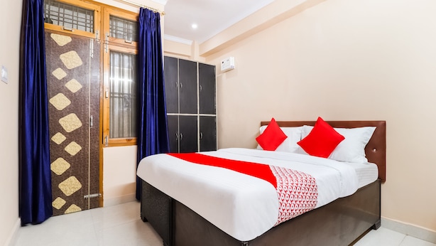 Une chambre à coucher avec un lit, une armoire et une fenêtre avec des rideaux.