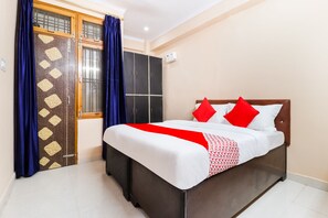 A bedroom with a bed, a wardrobe, and a window with curtains. - OYO 61469 Kalawati Palace (Bakshi Ka Talab)