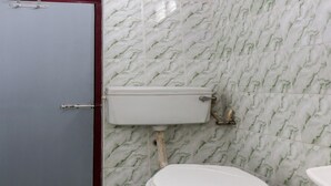 Un bagno con un water, una parete a effetto marmo e una porta.