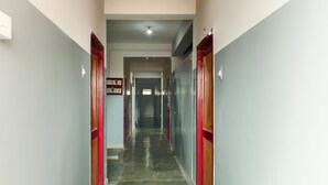 Un lungo e stretto corridoio con pavimento in pietra lucida e porte sagomate in rosso su entrambi i lati.